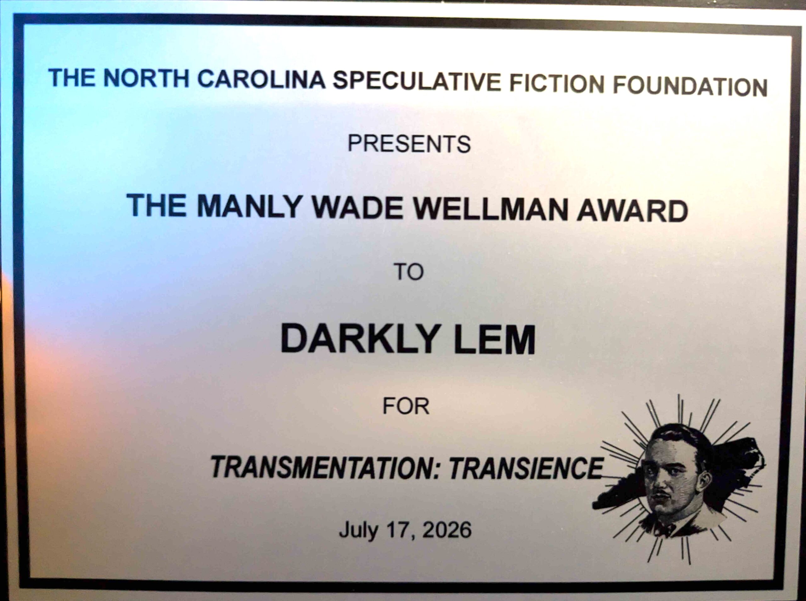 A plaque reading: THE NORTH CAROLINA SPECULATIVE FICTION FOUNDATION PRESENTS THE MANLY WADE WELLMAN AWARD TO DARKLY LEM FOR TRANSMENTATION: TRANSIENCE July 17, 2026